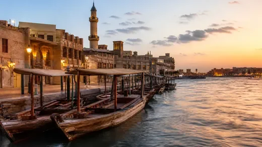 Wooden abras moored along Dubai Creek at dusk (AI-generated image)